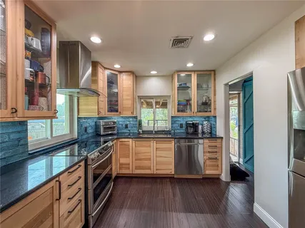 a kitchen with stainless steel appliances granite countertop lots of counter top space and wooden floor