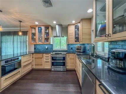 a kitchen with stainless steel appliances kitchen island granite countertop a stove and cabinets