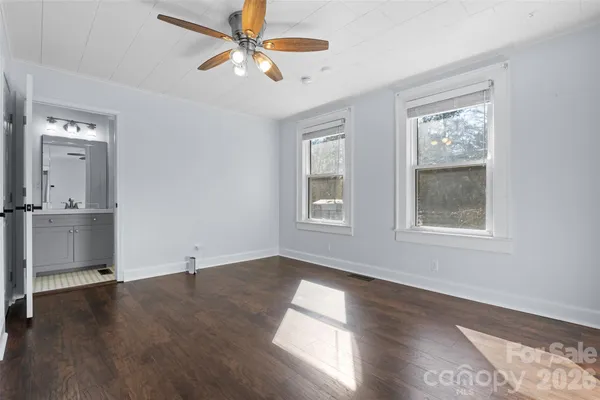 an empty room with wooden floor a ceiling fan and windows