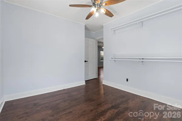 an empty room with wooden floor and fan