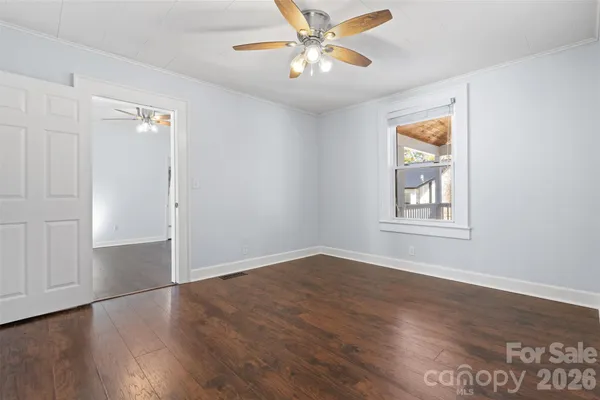 a view of an empty room with window and wooden floor