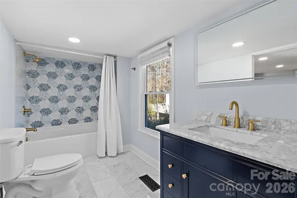 a bathroom with a granite countertop sink a toilet a mirror a vanity and shower