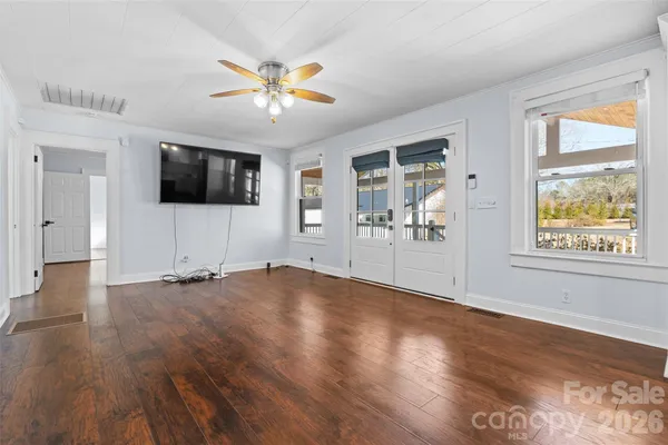a view of a livingroom with a flat screen tv wooden floor and a window