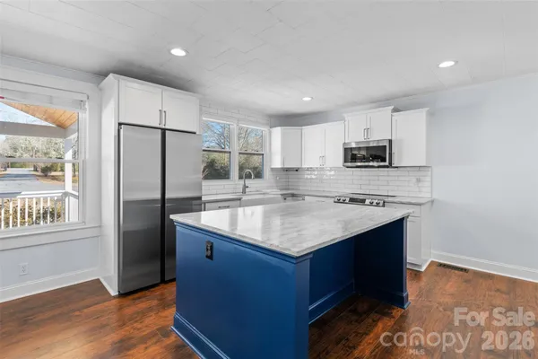 a kitchen with kitchen island granite countertop a sink stove and refrigerator