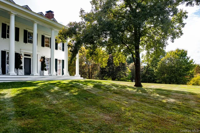 a white house that has a small yard and trees in the background