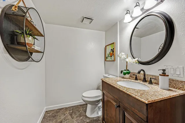 a bathroom with a granite countertop toilet sink mirror and vanity