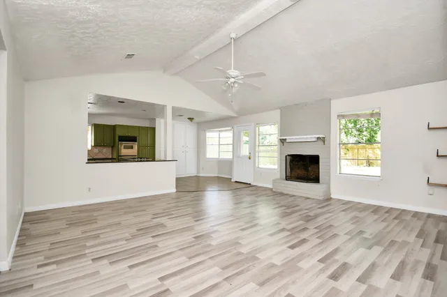 an empty room with windows fireplace and sink