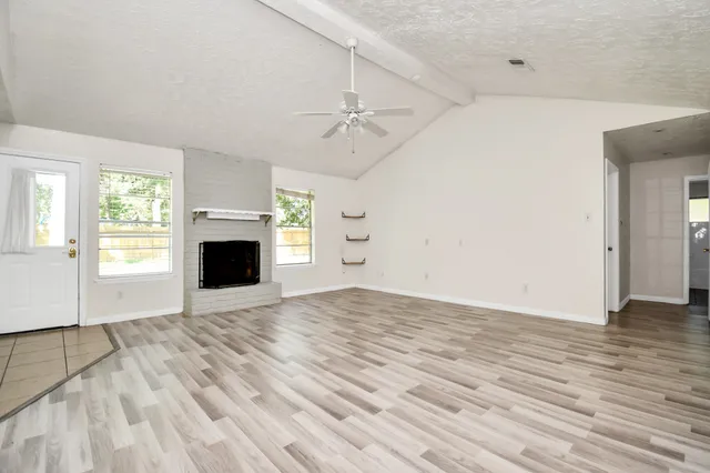 an empty room with windows and fireplace
