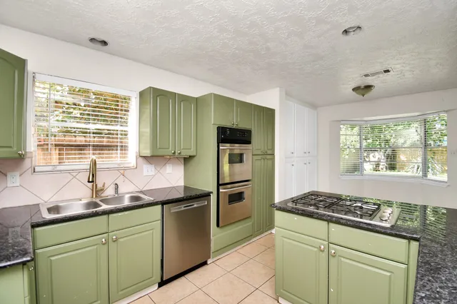 a kitchen with granite countertop a sink stainless steel appliances and window