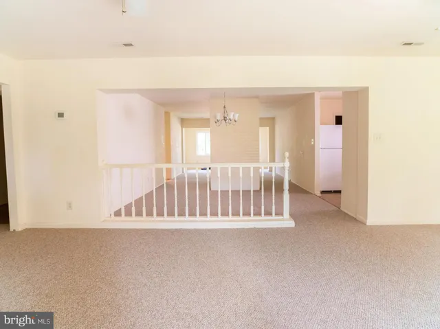 an empty room with chandelier fan and windows