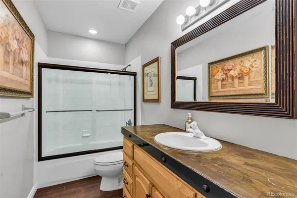 a bathroom with a granite countertop sink toilet and large mirror