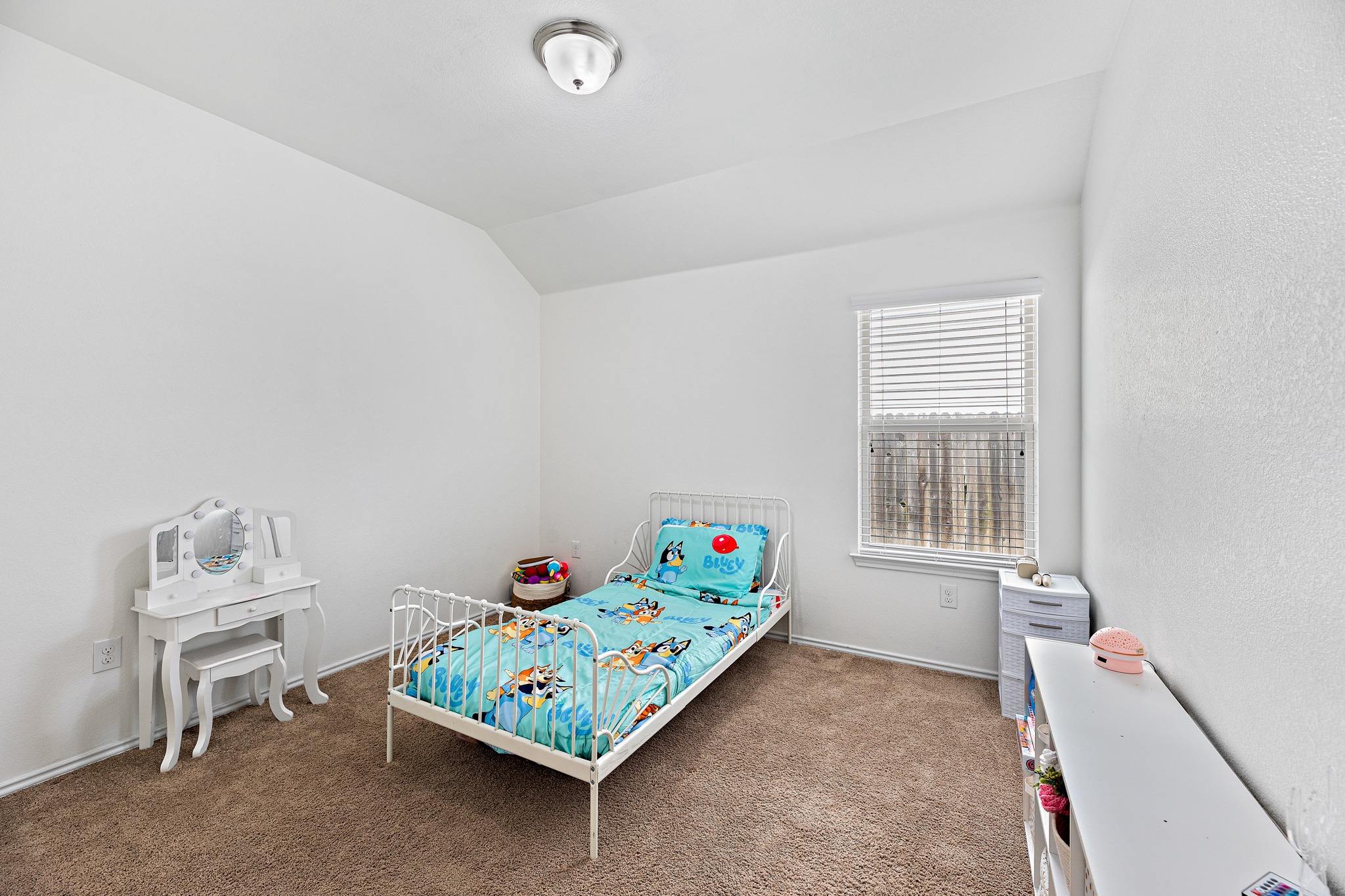 382 Limerick Road Buda, TX 78610 - Photo 9 of 20 A cozy bedroom features sloped ceilings, plush carpet, and natural light from a window with blinds.