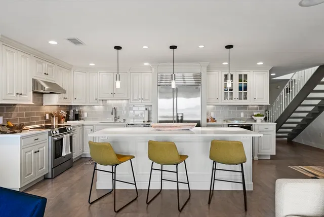 a kitchen with kitchen island a stove a table and chairs in it
