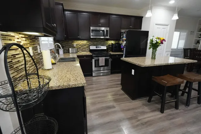 a kitchen with stainless steel appliances granite countertop a table chairs and a refrigerator