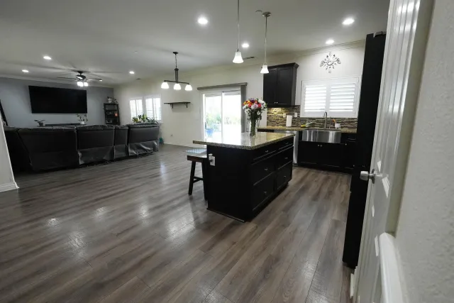 a open kitchen with stainless steel appliances kitchen island granite countertop a refrigerator stove and a sink with large countertops