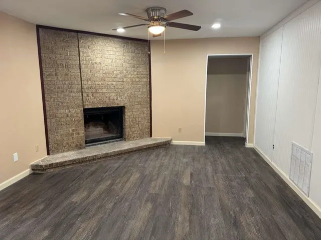 an empty room with wooden floor a fireplace and windows