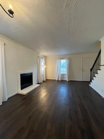 an empty room with wooden floor fireplace and windows