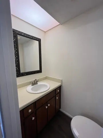 a bathroom with a toilet sink vanity and mirror