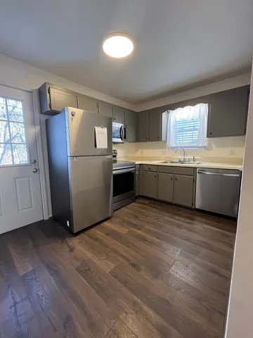 a kitchen with stainless steel appliances granite countertop a refrigerator a sink dishwasher and wooden floor