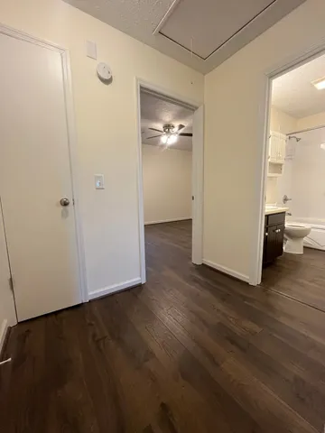 a view of an empty room with wooden floor and a bathroom
