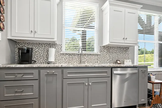 a kitchen with granite countertop white cabinets and a window