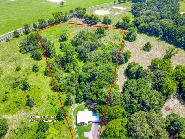 an aerial view of residential houses with outdoor space and trees all around