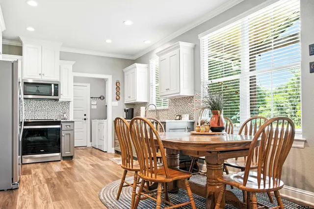a kitchen with stainless steel appliances kitchen island granite countertop a dining table chairs and a refrigerator