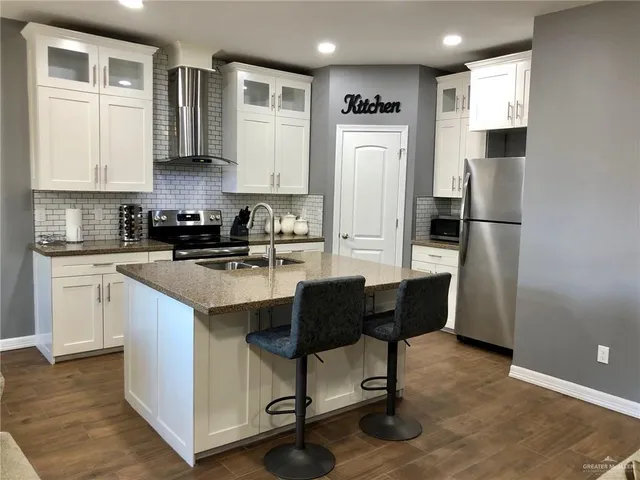 a kitchen with stainless steel appliances granite countertop a refrigerator and a stove top oven