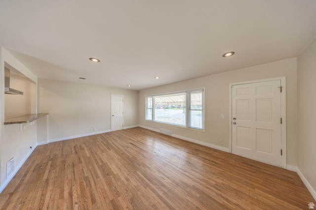 193 Locust Street Clearfield, UT 84015 - Photo 5 of 29 Spacious interior featuring wood flooring, recessed lighting, a large picture window with blinds, a six-panel entry door, and a built-in counter with an overhead stainless steel range hood