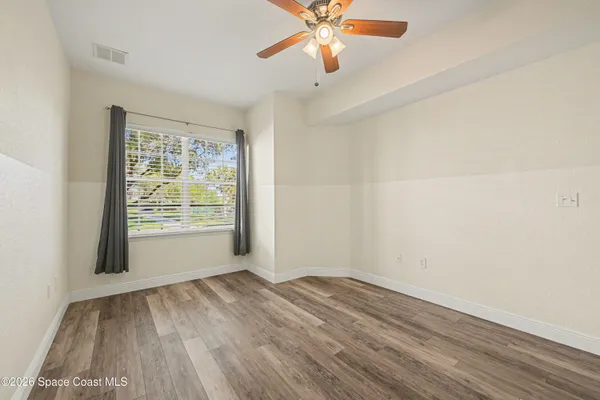 a view of a room with wooden floor and a ceiling fan