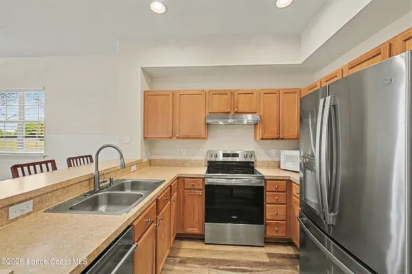 a kitchen with granite countertop a refrigerator stove and sink