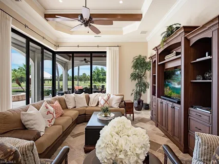 a living room with furniture a flat screen tv and a floor to ceiling window