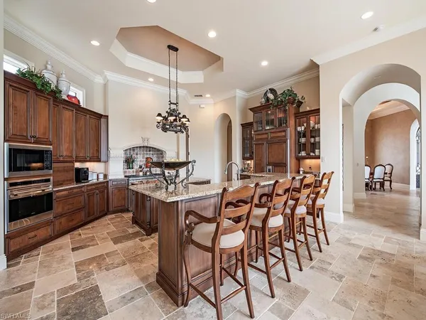 a kitchen with stainless steel appliances kitchen island granite countertop a dining table chairs and sink