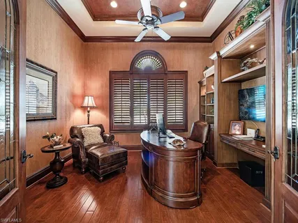 a bedroom with a bed a large window and wooden floor