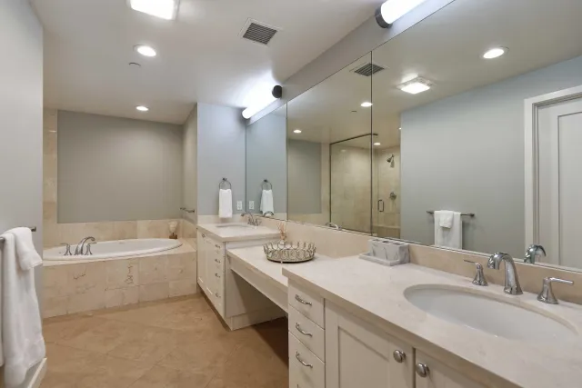a bathroom with a granite countertop sink a toilet a large mirror and shower