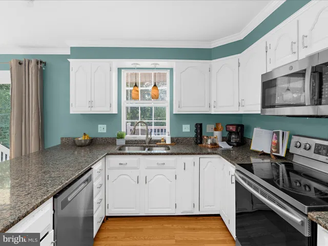 a kitchen with stainless steel appliances granite countertop a table chairs and wooden floor