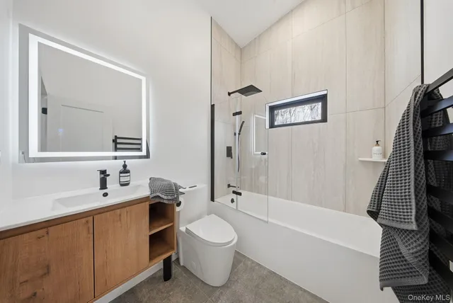 a bathroom with a bathtub shower sink vanity mirror and toilet