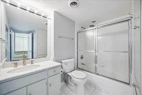 a bathroom with a shower sink vanity mirror and toilet