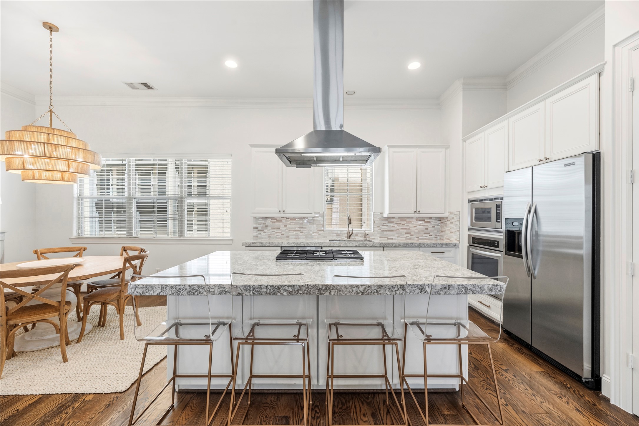 1537 Haddon Street Houston, TX 77006 - Photo 15 of 48 This modern kitchen features an open layout with a large island, granite countertops, and stainless steel appliances. It includes a cozy dining area with wood flooring, creating a warm and inviting space.