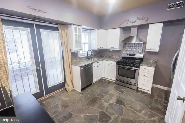 a kitchen with stainless steel appliances granite countertop a stove a sink and a refrigerator