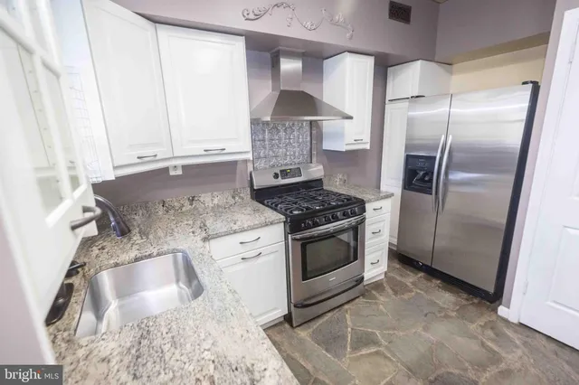 a kitchen with granite countertop a stove and a refrigerator