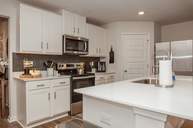 a kitchen with white cabinets and stainless steel appliances