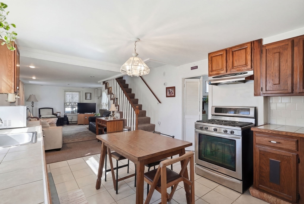 1080 Shirley Street Winthrop, MA 02152 - Photo 2 of 21 a open kitchen with stainless steel appliances granite countertop a stove top oven a sink dishwasher a dining table and chairs with wooden floor