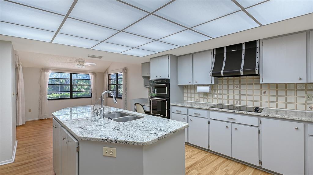 4674 Hidden River Road Sarasota, FL 34240 - Photo 11 of 46 a kitchen with granite countertop kitchen island stainless steel appliances a sink stove and cabinets