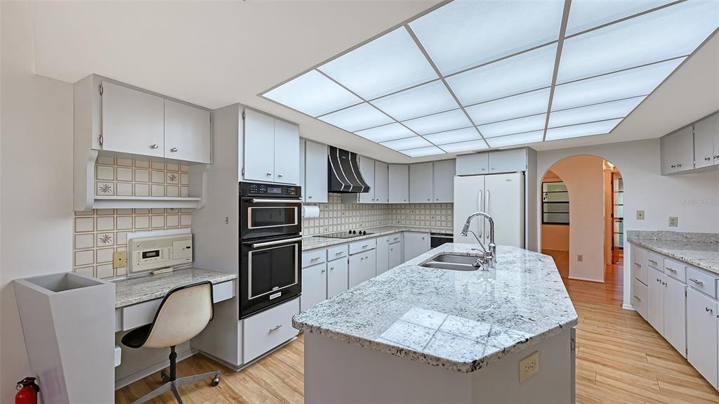 4674 Hidden River Road Sarasota, FL 34240 - Photo 10 of 46 a kitchen with granite countertop kitchen island stainless steel appliances a sink stove and refrigerator