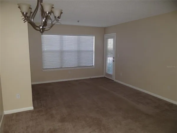 an empty room with windows and chandelier fan