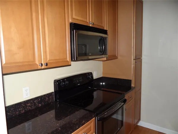 a kitchen with granite countertop white cabinets and black appliances