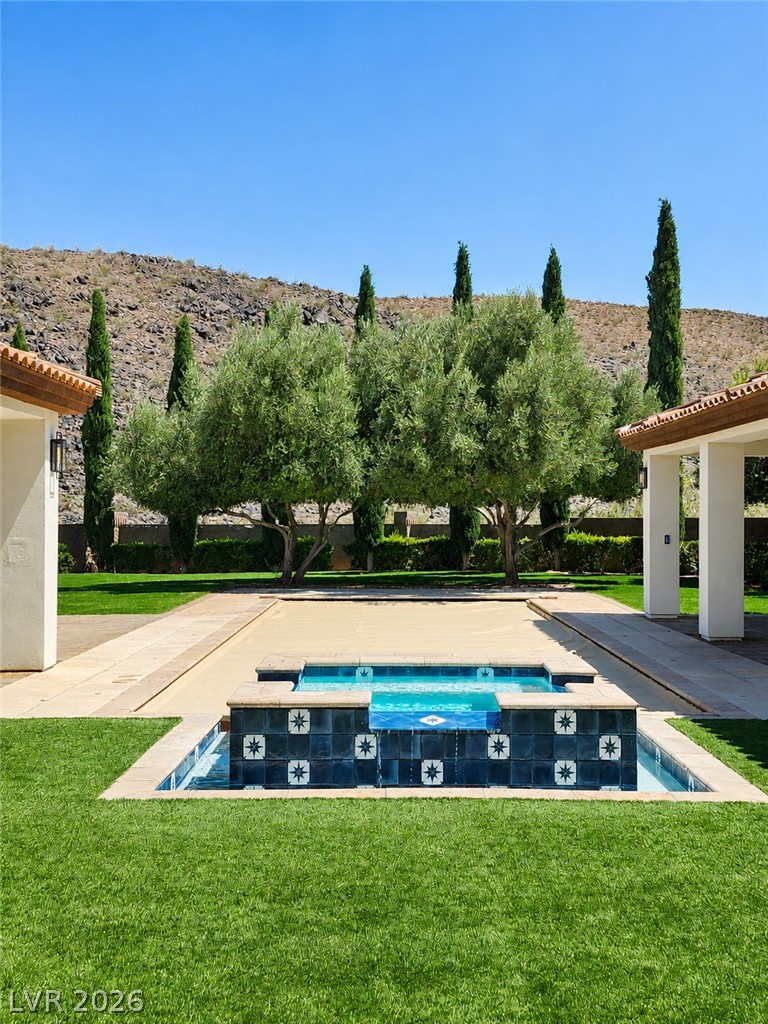 1140 Julie Road Henderson, NV 89002 - Photo 15 of 85 A tiered water feature with decorative tiling creates a serene oasis amidst verdant lawns.