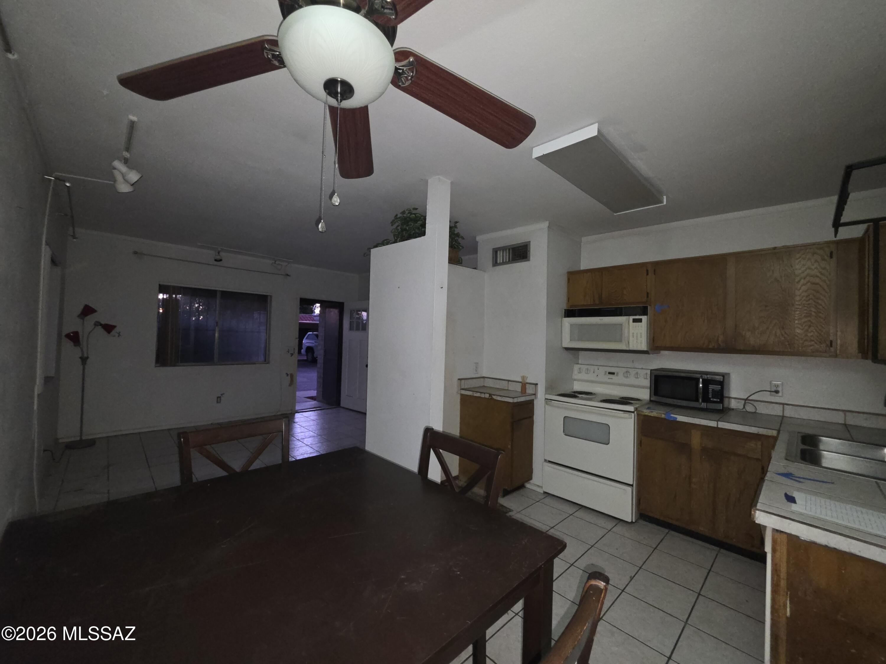 211 West Roger Road, Unit 24 Tucson, AZ 85705 - Photo 2 of 24 a kitchen with stainless steel appliances granite countertop a stove a refrigerator a sink dishwasher a dining table and chairs with wooden floor
