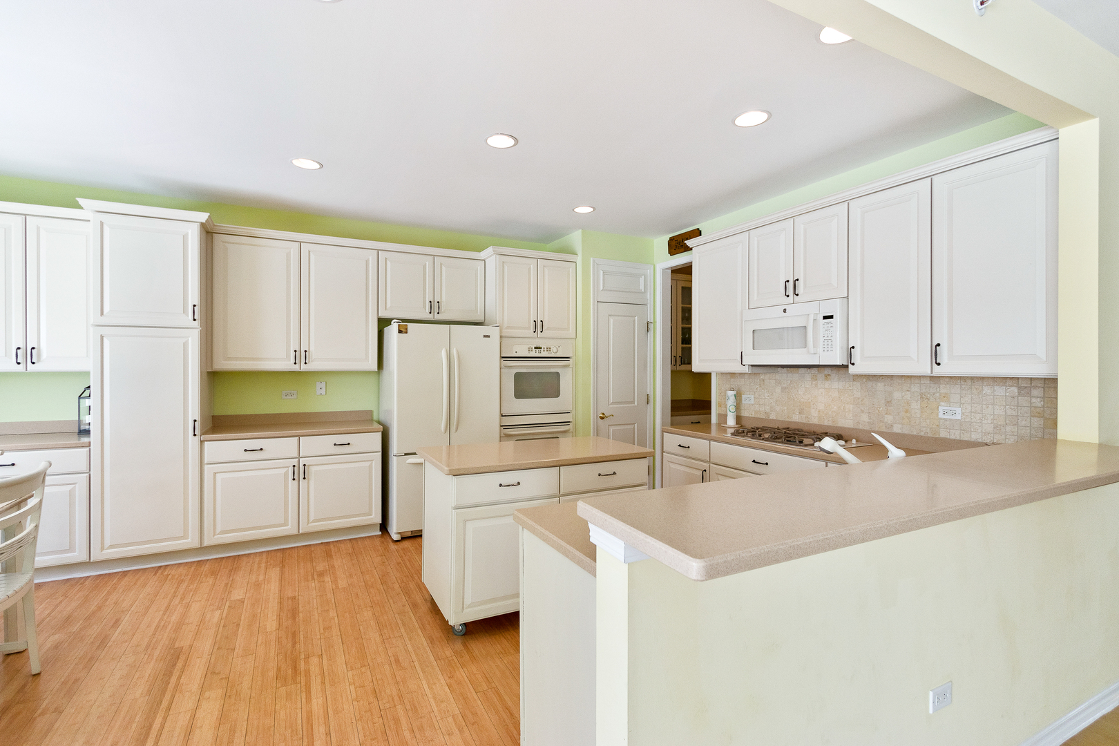 12614 Raintree Path Huntley, IL 60142 - Photo 7 of 28 a kitchen with granite countertop a refrigerator sink stove and white cabinets with wooden floor